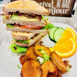 plate filled with a stacked sandwich, fruits and veggies