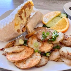 plate of breakfast burrito wrap with veggies and fruits